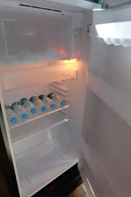 an empty refrigerator with its door open with blue bottles at Rawi Seaside Cottage, Ko Yao Noi in Ban Laem Sai