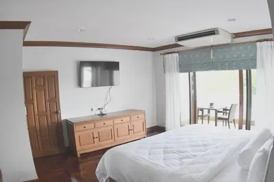 a bedroom with a bed and a dresser and a window at Blue Canyon Country Club Golf Course Maikhao in Phuket