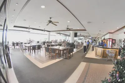 a restaurant with tables and chairs and people walking around at Blue Canyon Country Club Golf Course Maikhao in Phuket