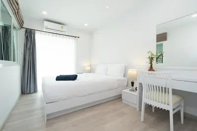 a white bedroom with a white bed and a chair at Phuket Villa 1 bedroom apartment in Patong in Patong Beach