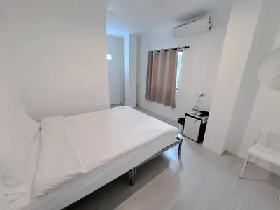 a white bedroom with a bed and a chair at XX BAO Patong Beach Phuket II เบา ป่าตอง บีช ภูเก็ต in Patong Beach