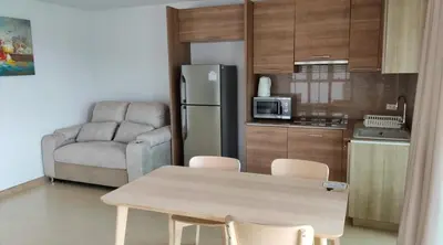 a kitchen with a table and a refrigerator and a couch at Thebirdhouse Patong Phuket 301 in Patong Beach