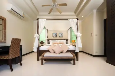 a bedroom with a bed with a chair and a ceiling fan at Prima Karon Villa in Karon Beach