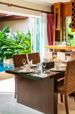 a restaurant with a table with wine glasses and chairs at Prima Karon Villa in Karon Beach
