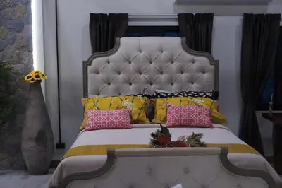 a bed with pink and yellow pillows on it at Villa Omloft in Changwat Phuket
