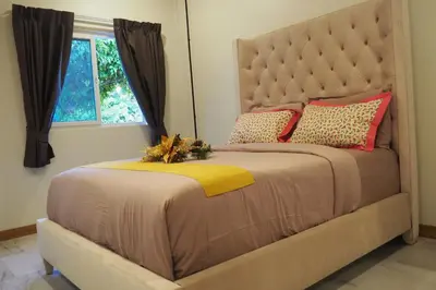 a bed with a large headboard and a window at Villa Omloft in Changwat Phuket