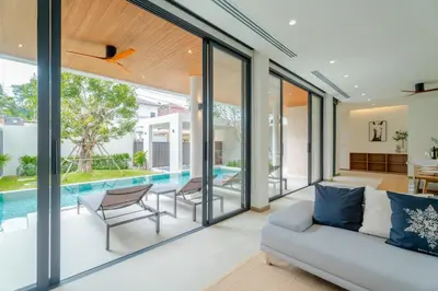 an open living room with glass doors and a pool at Liva Villa near Rawai Phuket in Ban Saiyuan (1)