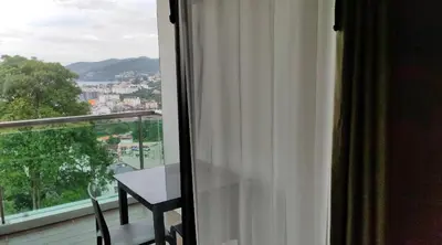 a room with a window with a table on a balcony at Thebirdhouse Patong Phuket 302 in Patong Beach