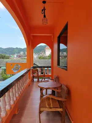 an orange room with a table and chairs on a balcony at myPatong Social Hostel in Patong Beach