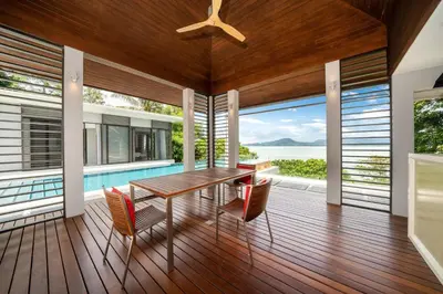 a dining room with a table and chairs on a deck at Exclusive Oceanfront Living, 5BR Pool Villa Elegance in Ko Lek