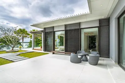 an outdoor patio with chairs and tables on a house at Exclusive Oceanfront Living, 5BR Pool Villa Elegance in Ko Lek