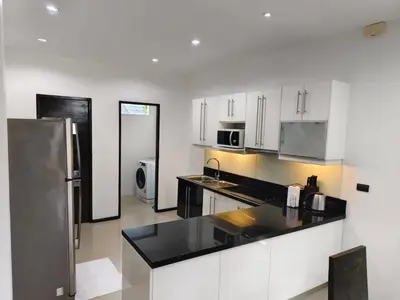 a kitchen with white cabinets and a stainless steel refrigerator at Oxygen Villa 3 beds in Rawai Beach
