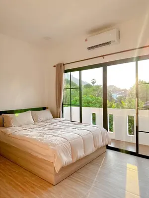 a bedroom with a large bed and a large window at Luxsabai home in Ban Phlu Yai