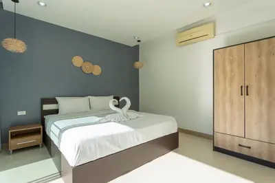 a bedroom with a large bed and a wooden cabinet at V129 Walking To Award winning Naiharn Beach 4BR in Rawai Beach