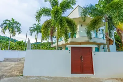 a house with a red door and palm trees at V129 Walking To Award winning Naiharn Beach 4BR in Rawai Beach