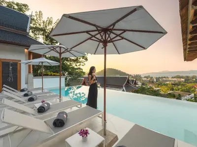 a woman standing on the edge of a swimming pool with an umbrella at Baan View Talay - Sea View Zenith Villa By Elite Havens in Surin Beach