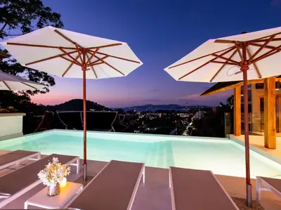 a swimming pool with two white umbrellas at Baan View Talay - Sea View Zenith Villa By Elite Havens in Surin Beach