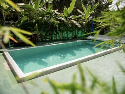 a swimming pool in a garden with plants at Los Patios Hostel Phuket in Mai Khao Beach