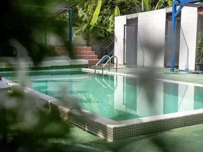 a swimming pool with blue water in a building at Los Patios Hostel Phuket in Mai Khao Beach