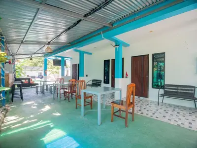 a dining room with tables and chairs and blue beams at Los Patios Hostel Phuket in Mai Khao Beach
