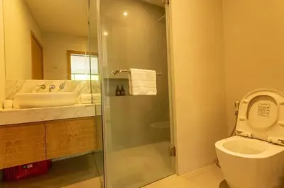 a bathroom with a shower and a toilet and a sink at V91 Where The Rich People Go Trichada Resort in Thalang