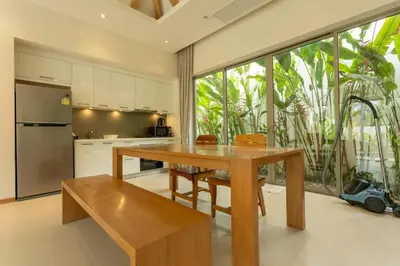a kitchen with a wooden table and a large window at V91 Where The Rich People Go Trichada Resort in Thalang