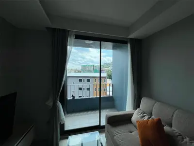a living room with a couch and a large window at Condo Surin-Bangtao Beach in Surin Beach