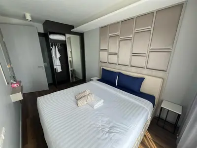 a bedroom with a large bed with blue pillows at Condo Surin-Bangtao Beach in Surin Beach