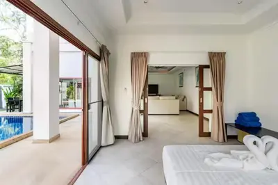 a bedroom with a bed and a view of a pool at Surin villa by Pattara in Surin Beach