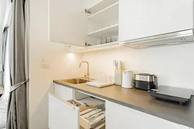 a kitchen with white cabinets and a sink at Large condo Surin-Bangtao Beach in Surin Beach