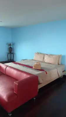 a bed with a red couch in a room at Thebirdhouse Patong Phuket203 in Patong Beach