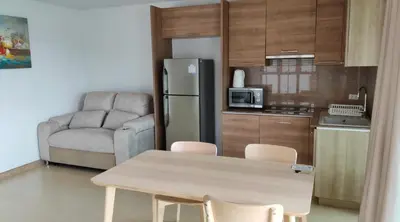 a kitchen with a table and a refrigerator and a couch at Thebirdhouse Patong Phuket 202 in Patong Beach