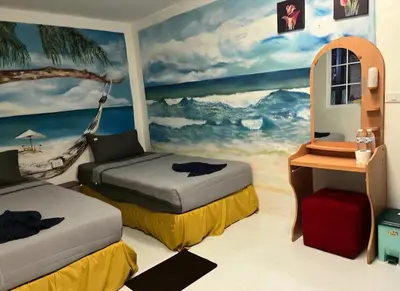 a room with two beds and a painting of a beach at Reggaein in Phi Phi Don