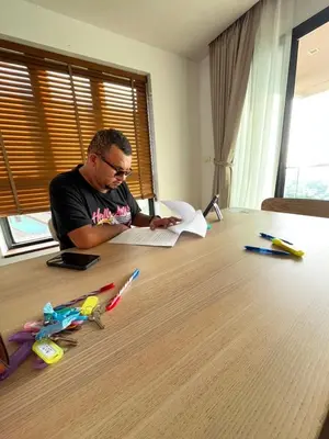 a man is sitting at a table writing on a paper at Thebirdhouse Patong Phuket303 in Patong Beach