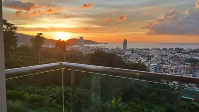 a view of a city at sunset from a balcony at Thebirdhouse Patong Phuket303 in Patong Beach