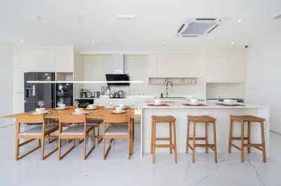 a white kitchen with a wooden table and chairs at Modern Elegance & Tropical Vibe - 4BR Pool Villa in New Build Residence Lux Pride 2 V10 in Bang Tao Beach