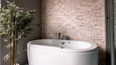 a white bath tub in a bathroom with a brick wall at Cozy studio near Bangtao Beach in Bang Tao Beach