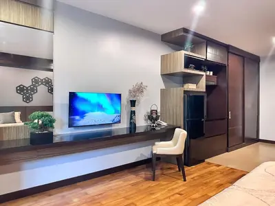 a living room with a tv and a table with a chair at Cozy studio near Bangtao Beach in Bang Tao Beach