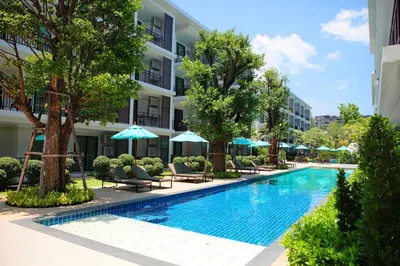 a swimming pool with chairs and umbrellas next to a building at Title III Condo Rawai, 1 bedroom in Phuket Town