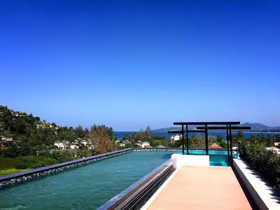 a swimming pool with a wooden walkway next to the water at Condo Surin-Bangtao Beach in Surin Beach
