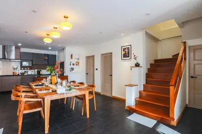 a kitchen and dining room with a wooden table and stairs at Summer Villa Patong in Patong Beach
