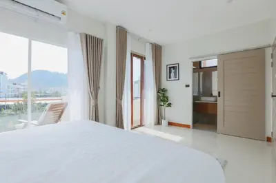 a white bedroom with a large bed and a window at Summer Villa Patong in Patong Beach