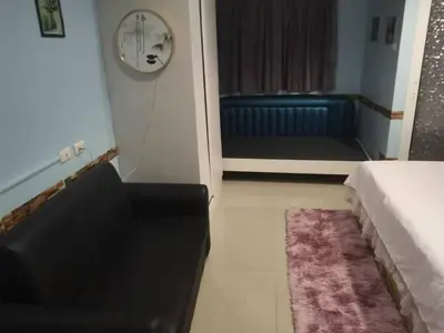a living room with a couch and a door with a clock at \u5927\u53d4\u7684\u5c0f\u5c4b in Patong Beach