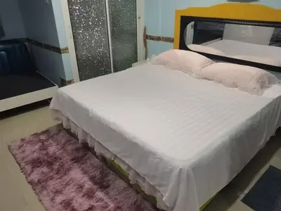 a bedroom with a large white bed with a pink rug at \u5927\u53d4\u7684\u5c0f\u5c4b in Patong Beach