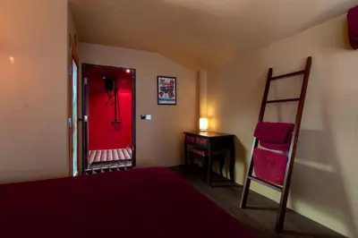 a bedroom with a red door and a ladder and a chair at Ḥokma Boutique Hotel & Tropical Lounge in Phi Phi Don