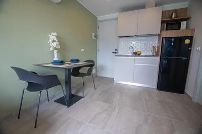 a kitchen with a table and chairs and a black refrigerator at Thai Me Up the Tower in Ban Klang