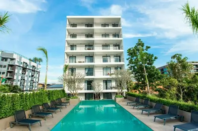 an apartment building with a swimming pool and chairs at Thai Me Up the Tower in Ban Klang