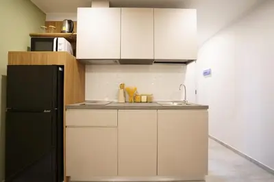 a kitchen with white cabinets and a black refrigerator at Thai Me Up the Tower in Ban Klang