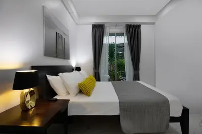 a bedroom with a bed with a desk and a window at Villa Homey in Patong Beach