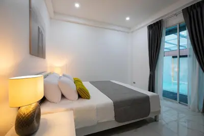 a bedroom with a bed with a lamp and a window at Villa Homey in Patong Beach